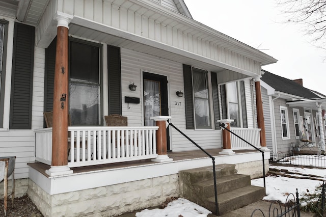 snow covered property entrance featuring covered porch