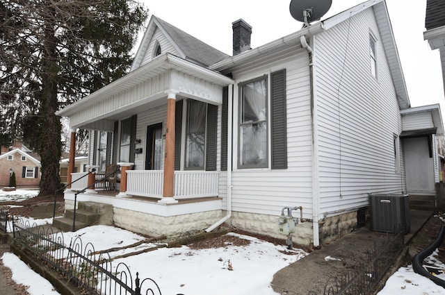 snow covered property featuring cooling unit and a porch