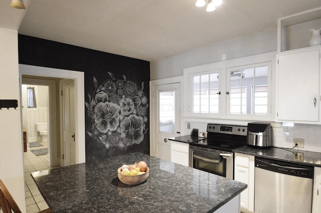 kitchen featuring light tile patterned floors, appliances with stainless steel finishes, tasteful backsplash, white cabinets, and dark stone counters