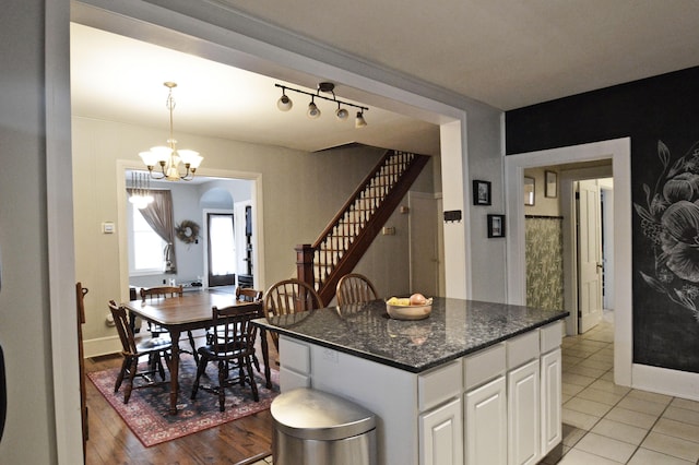 kitchen featuring an inviting chandelier, dark stone countertops, a kitchen island, pendant lighting, and white cabinets