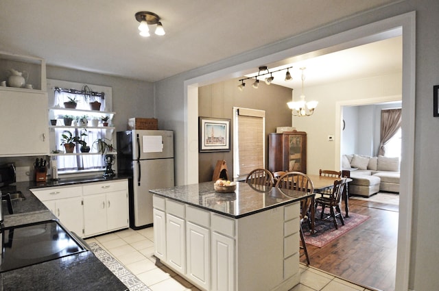 kitchen with white cabinetry, a notable chandelier, stainless steel fridge, and light tile patterned floors