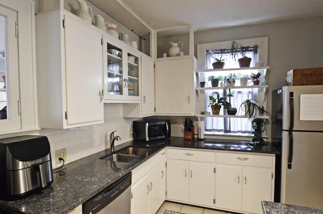 kitchen featuring sink, stainless steel appliances, tasteful backsplash, white cabinets, and dark stone counters