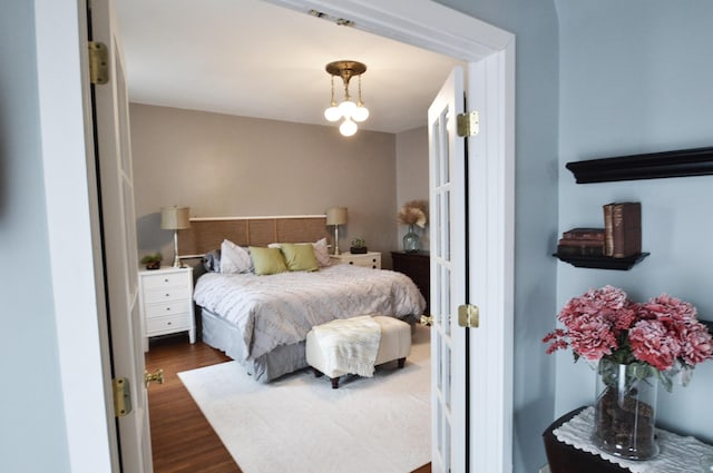 bedroom featuring an inviting chandelier and dark hardwood / wood-style floors