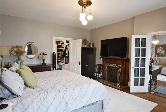 bedroom featuring a fireplace, dark hardwood / wood-style flooring, a walk in closet, a closet, and a chandelier