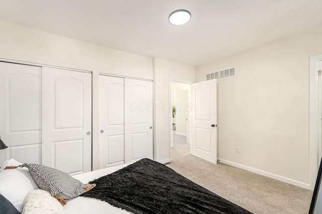 bedroom with two closets and light colored carpet