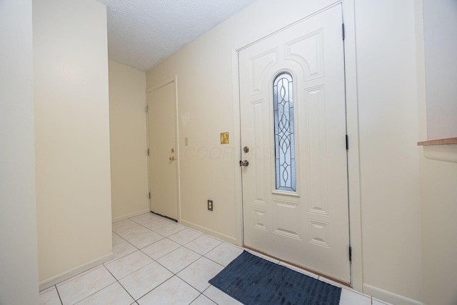 entryway with light tile patterned floors and a textured ceiling