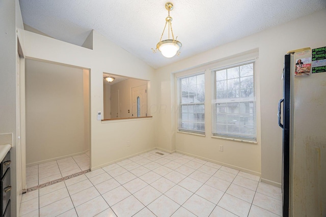 unfurnished dining area with vaulted ceiling, a textured ceiling, and light tile patterned floors