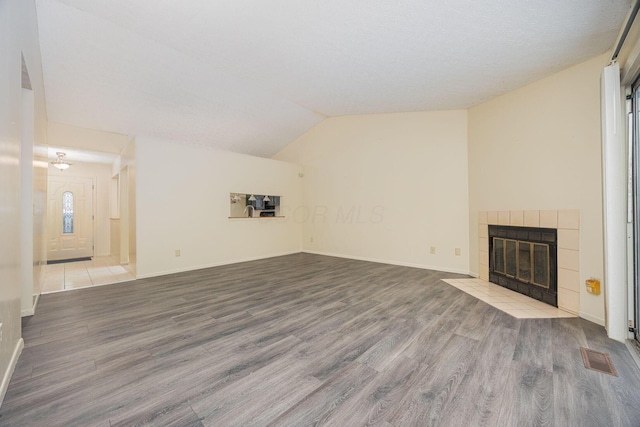 unfurnished living room featuring a fireplace, vaulted ceiling, and light hardwood / wood-style floors