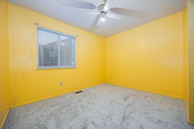 carpeted empty room with ceiling fan and a textured ceiling