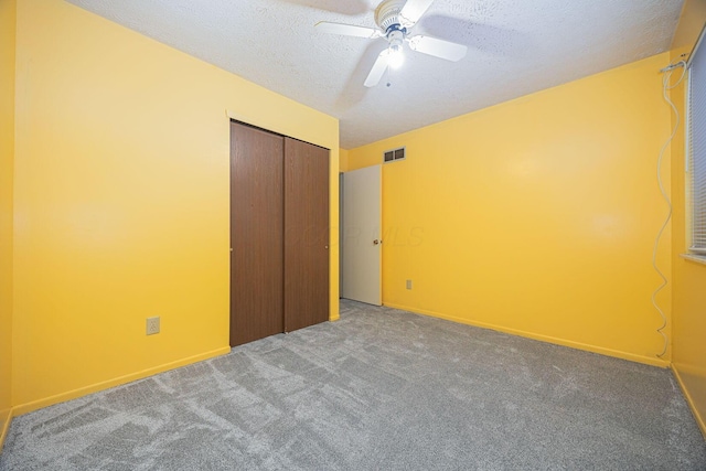 unfurnished bedroom featuring ceiling fan, carpet floors, a closet, and a textured ceiling