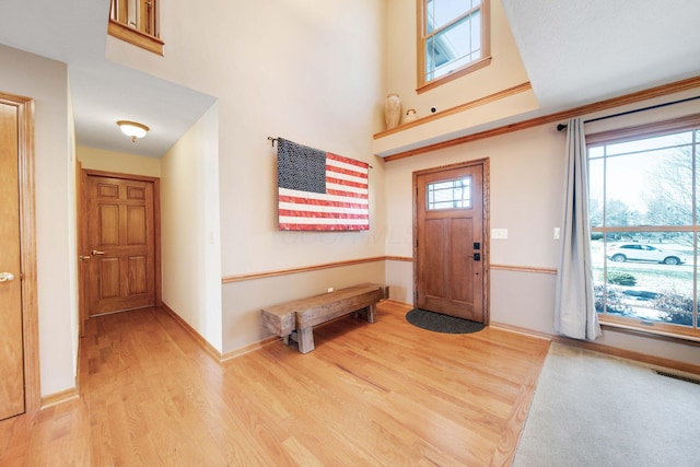 entrance foyer with a towering ceiling and light hardwood / wood-style floors