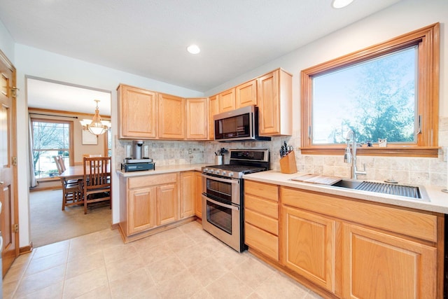 kitchen featuring pendant lighting, sink, stainless steel appliances, and light brown cabinets