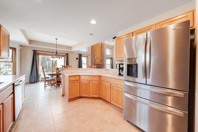 kitchen featuring hanging light fixtures, light tile patterned floors, a raised ceiling, a notable chandelier, and stainless steel appliances