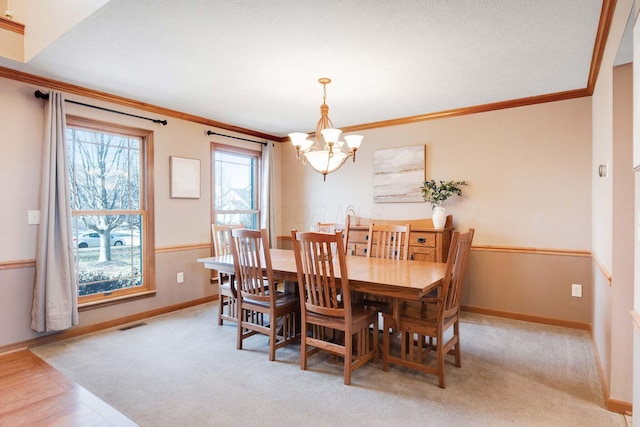 carpeted dining room featuring an inviting chandelier and ornamental molding