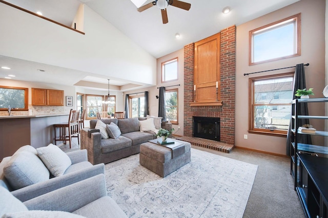 carpeted living room featuring ceiling fan, a brick fireplace, sink, and high vaulted ceiling