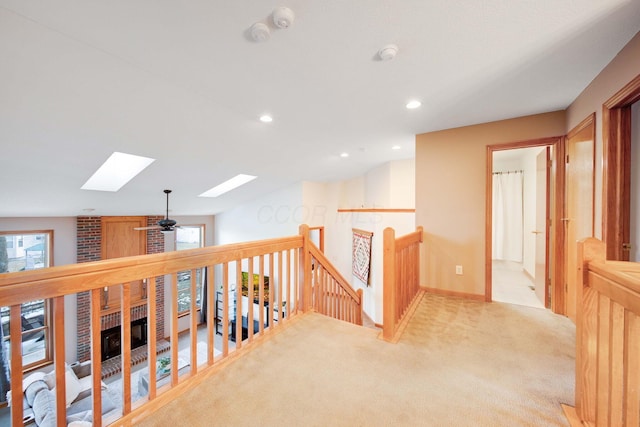 corridor with vaulted ceiling with skylight and light carpet