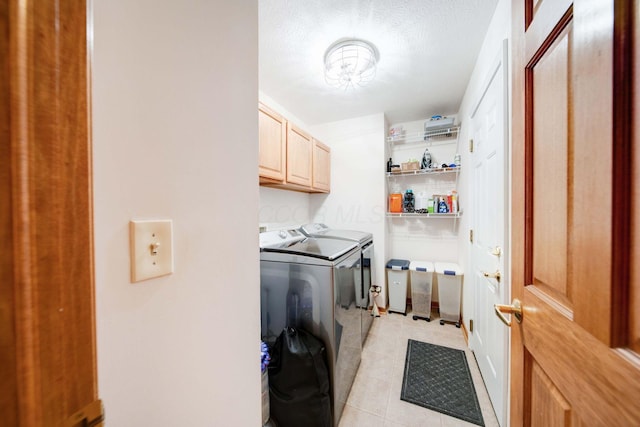 washroom featuring cabinets, light tile patterned flooring, a textured ceiling, and washer and clothes dryer