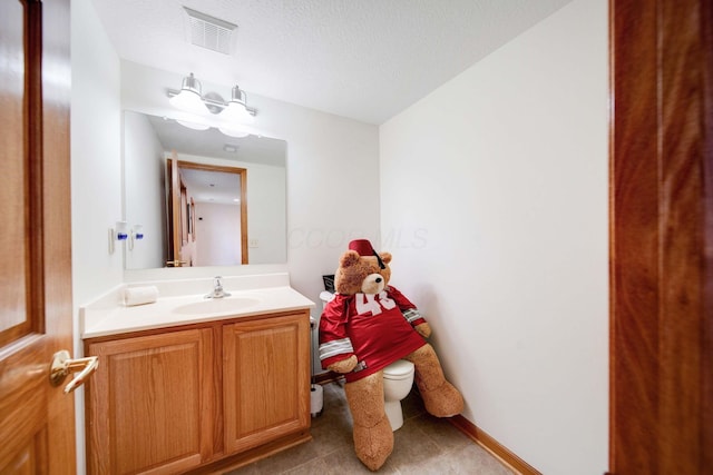 bathroom with tile patterned flooring, vanity, a textured ceiling, and toilet