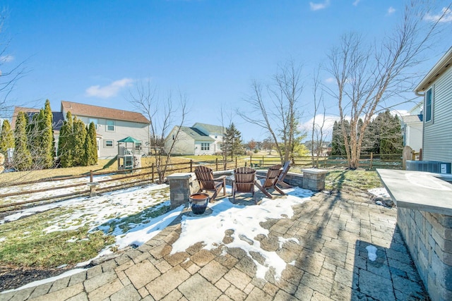 snow covered patio with a playground and an outdoor fire pit