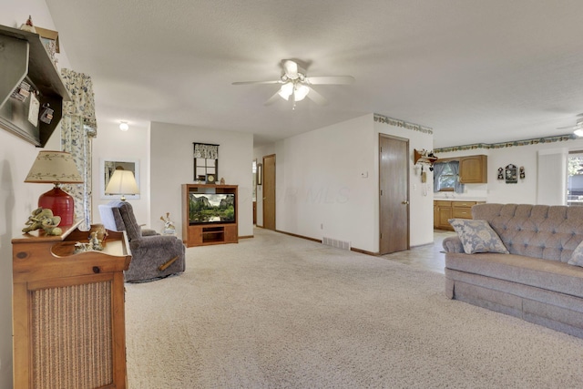 living room with baseboards, a ceiling fan, visible vents, and light carpet