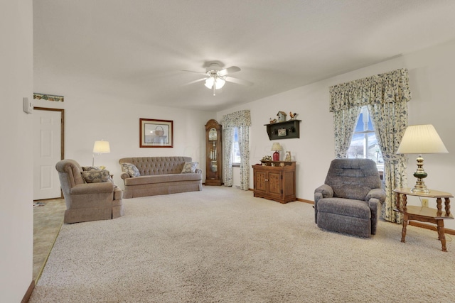 living area featuring a wealth of natural light, carpet flooring, baseboards, and a ceiling fan