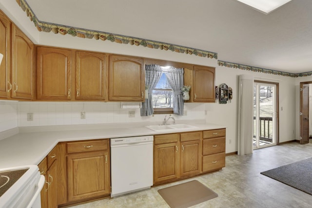 kitchen with light floors, dishwasher, a wealth of natural light, brown cabinets, and a sink