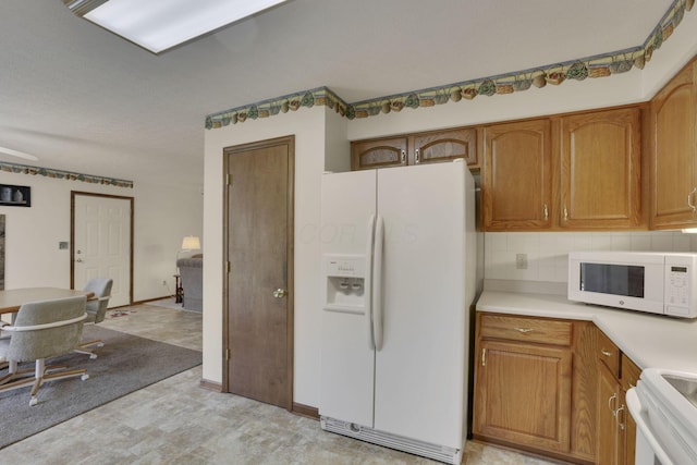 kitchen featuring white appliances, backsplash, brown cabinets, and light countertops