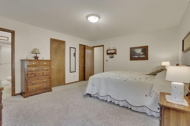 carpeted bedroom featuring ensuite bath and a textured ceiling