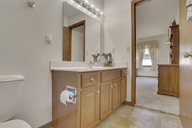 half bath featuring toilet, vanity, and baseboards