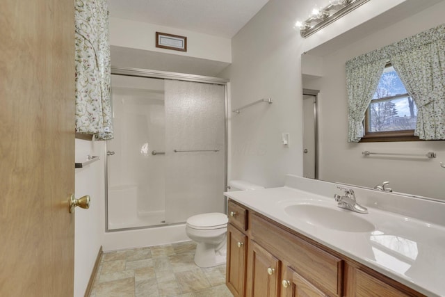 bathroom with vanity, a shower stall, and toilet