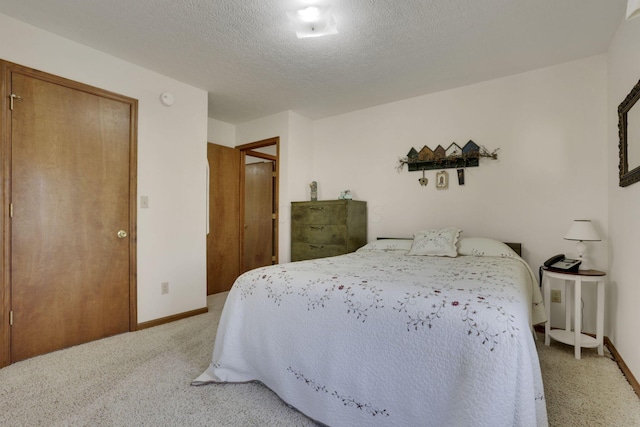 bedroom featuring light colored carpet, baseboards, and a textured ceiling