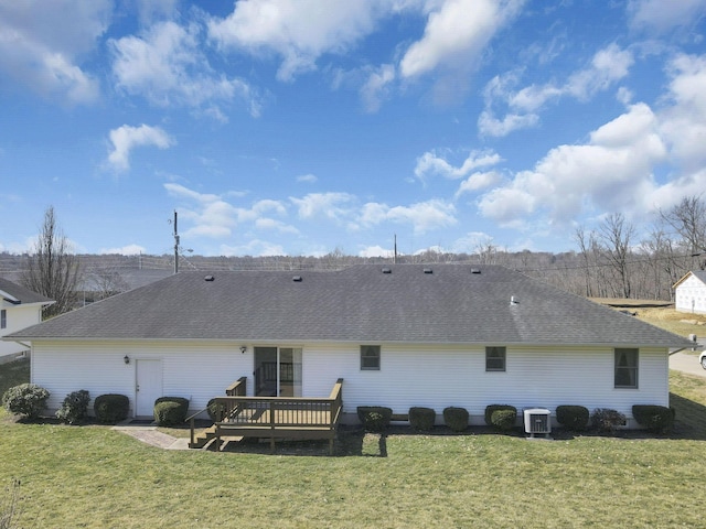 back of property with a shingled roof, a yard, and a wooden deck