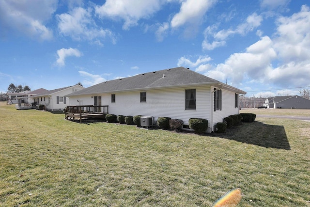 back of property featuring a yard, cooling unit, a deck, and a shingled roof