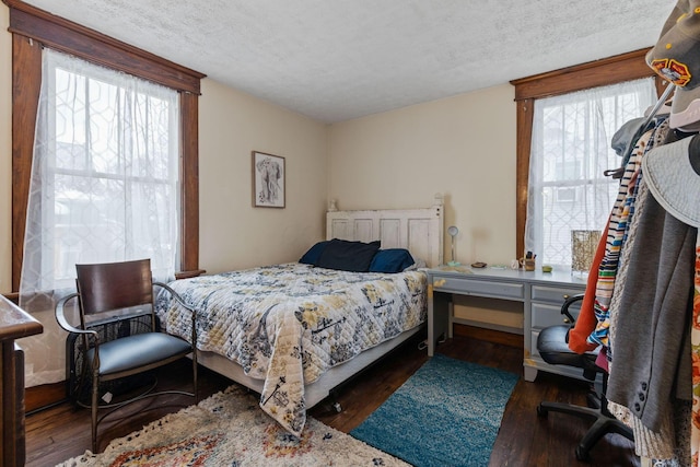 bedroom with multiple windows, dark hardwood / wood-style floors, and a textured ceiling