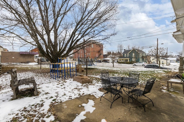 snow covered patio featuring a playground and a trampoline