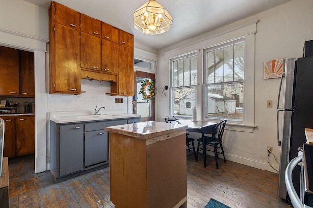 kitchen with sink, dark wood-type flooring, stainless steel refrigerator, a center island, and a chandelier