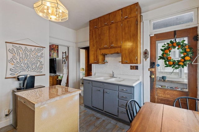 kitchen with sink, tasteful backsplash, a center island, dark hardwood / wood-style flooring, and a notable chandelier