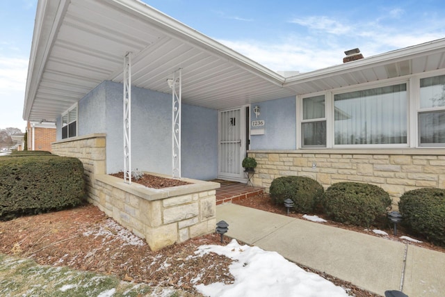 snow covered property entrance with covered porch