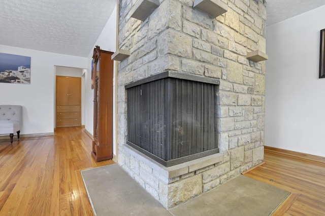 room details featuring a stone fireplace, hardwood / wood-style floors, and a textured ceiling