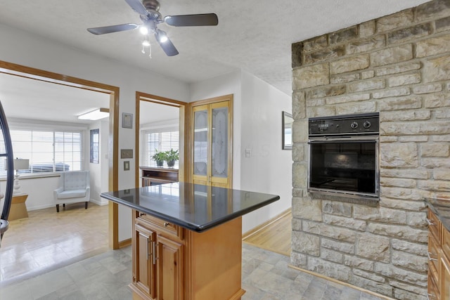 kitchen featuring black oven, a kitchen island, and a textured ceiling