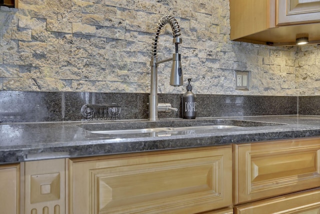 details featuring tasteful backsplash, dark stone countertops, sink, and light brown cabinets