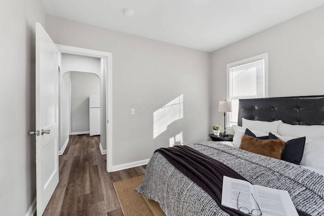 bedroom featuring white fridge and dark hardwood / wood-style flooring