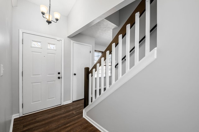 foyer entrance with dark hardwood / wood-style floors and an inviting chandelier