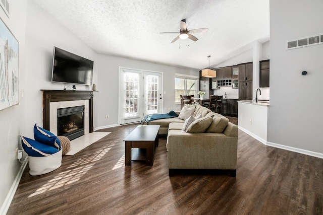 living room featuring lofted ceiling, a fireplace, dark hardwood / wood-style floors, and a textured ceiling