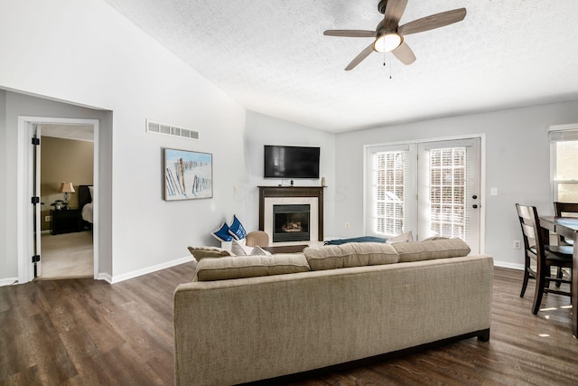 living room featuring dark wood-type flooring, ceiling fan, lofted ceiling, and a textured ceiling