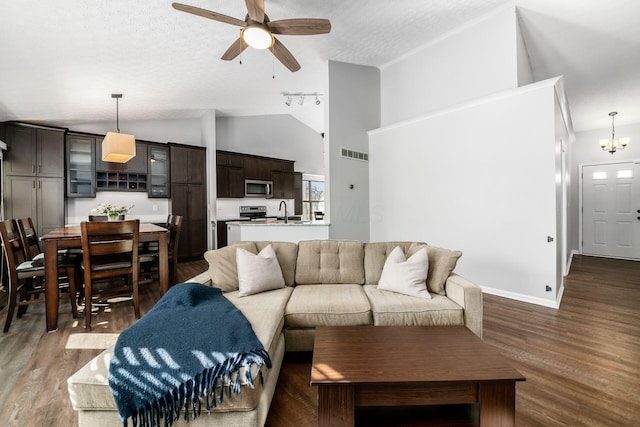 living room with sink, high vaulted ceiling, a textured ceiling, dark hardwood / wood-style flooring, and ceiling fan with notable chandelier