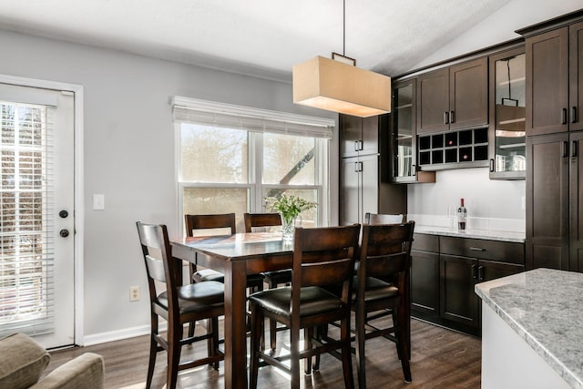 dining space featuring vaulted ceiling, indoor bar, and dark hardwood / wood-style floors