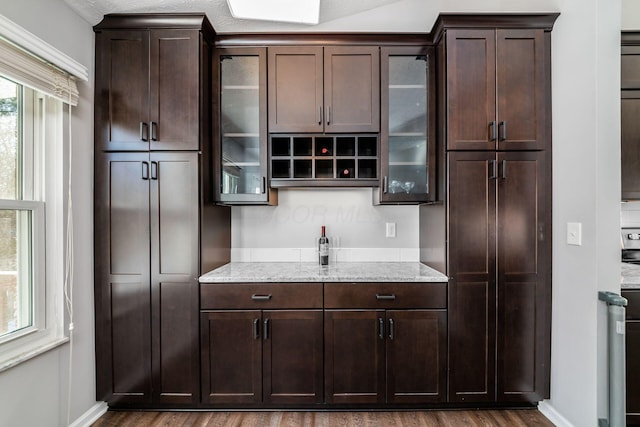 kitchen featuring light stone countertops, dark wood-type flooring, and dark brown cabinetry