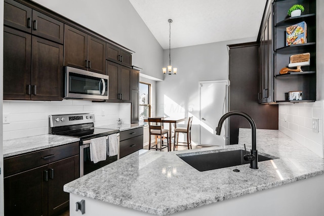 kitchen featuring appliances with stainless steel finishes, sink, light stone counters, and kitchen peninsula