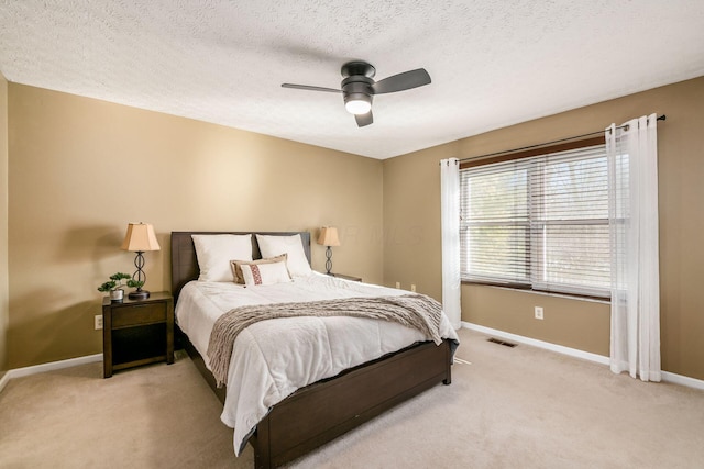 bedroom with a textured ceiling, light colored carpet, and ceiling fan